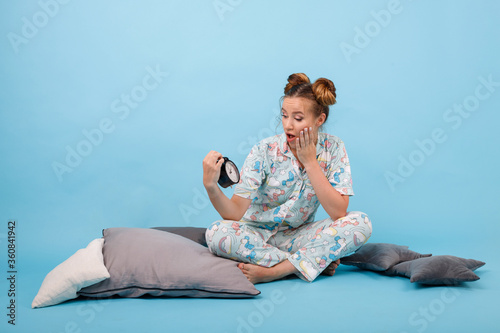 girl in pajamas and with an alarm clock on a blue background. Good morning