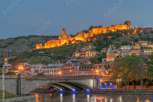 Cityscape of illuminated historic old Tbilisi with ancient Narikala fortress, Sioni Cathedral, Metechi stone Bridge over the Mtkvari/Kura river and mosque in the evening. Tbilisi, Georgia