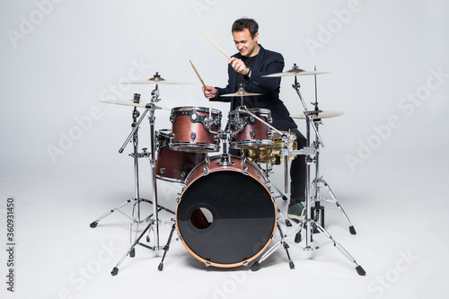 Young attractive man drummer playing drums and cymbals isolated on white background