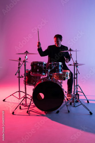 Young man drummer playing on drums on music concert. Club lights, artist show.