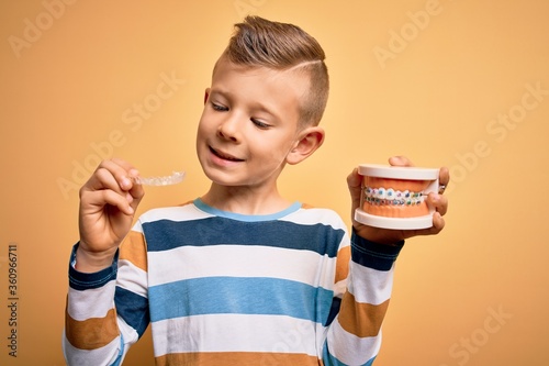 Little kid boy holding professional orthodontic denture with metal braces and removable invisible aligner. Comparation of two dental straighten treatments