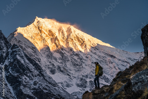 Young Asian woman standing in front of snow Himalaya mountain in a morning sunrise in Langtang valley, Nepal