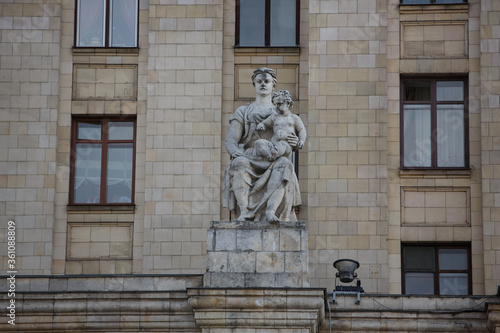 MOSCOW / RUSSIA - 20/04/2019 soviet communist stone sculpture of a sitting mother holding a baby child (sculptors Baburin, Nikogosyan, Anikushin) Kudrinskaya Square Building (Aviators' House) facade