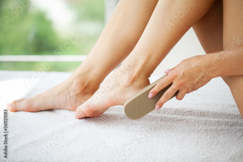 Woman cleans the heel of the foot with pumice