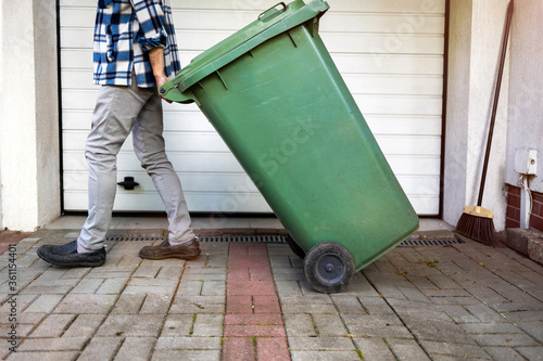 Senior man rolling garbage can 