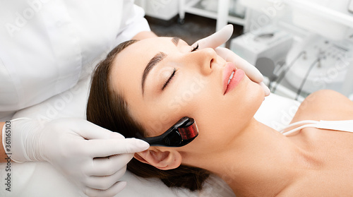 Beautician doing skin treatment using a microneedle derma roller. Woman getting procedure skincare, with mezzo skin roller