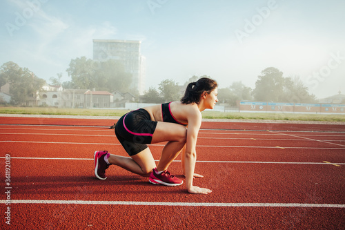 Athletic women in running start pose on running track