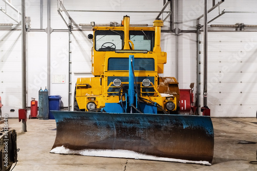 Large wheeled tractor with a dozer blade for clearing roads from snow