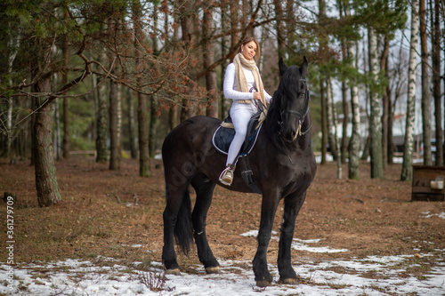 Beautiful girl with her Andalusian horse in the winter forest