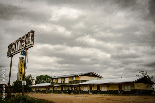 Rusty metal motel sign with wooden old motels under the cloudy and rainy sky