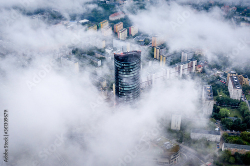 Aerial view from top on skyscraper Sky Tower in the fog in Wroclaw. Epic foggy morning in the city and tall building in the clouds. Wroclaw, Poland