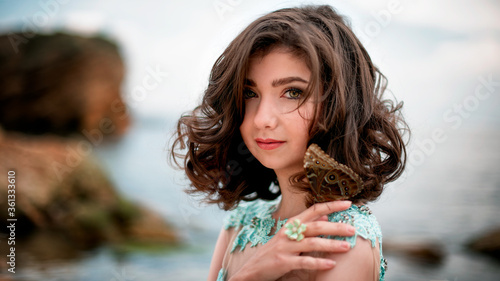 Beautiful young girl in a dress with butterflies on the beach. Portrait