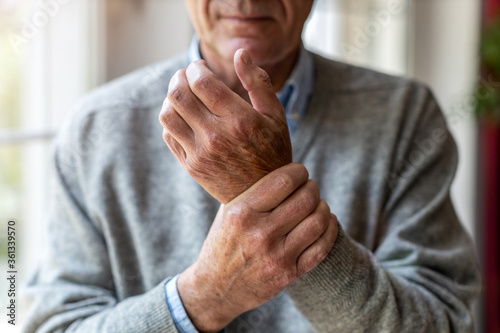 Senior man with arthritis rubbing hands 