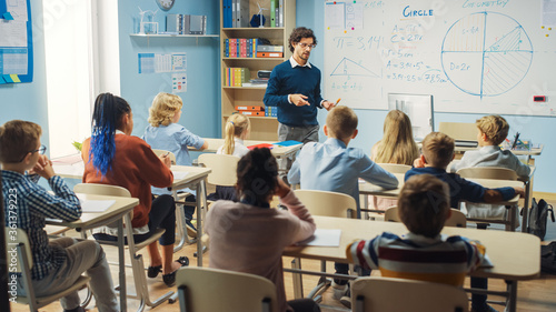 Elementary Classroom of Diverse Bright Children Listening Attentively to their Teacher Giving Lesson. Brilliant Young Kids in School Learning to Be Great Scientists, Doctors, Programmers, Astronauts