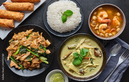 table of thai restaurant foods with green, pad see ew noodles and tom yum goong soup