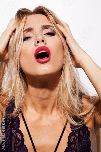 emotions and feelings concept - beautiful blond lady portrait in sexy lingerie while getting an orgasm on white background. Woman shouts in ecstasy in bright light