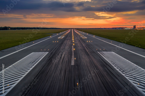 Used concrete asphalt airport empty runway with many braking marks, markings for landings and all navigation lights on. Clear for comercial airplane landing or taking off in Wroclaw airport