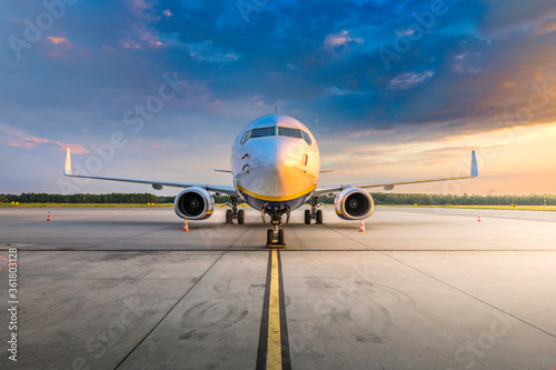 Modern commercial airplane in the parking lot of the airport apron, waiting for services maintenance, refilling fuel, and passenger boarding the plane. Concept of travel, holidays and business jet