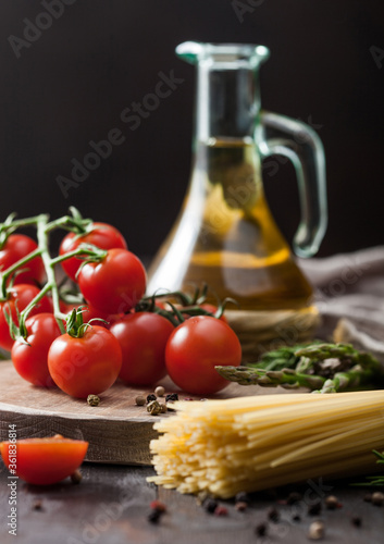 Spaghetti pasta with cherry tomatoes, olive oil with garlic and rosemary on wooden background.