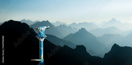 Public binoculars and Mountain Silhouettes at Sunrise. Foresight and vision for new business concepts and creative ideas. Alps, Allgau, Bavaria, Germany.