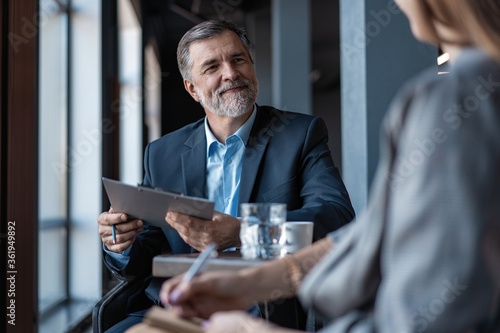 Image of mature businessman interviewing female.