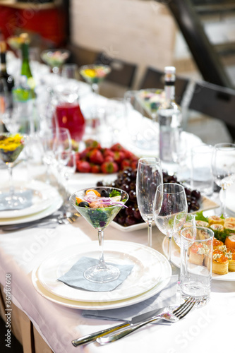White banquet table served with dishes, glasses and snacks at the event