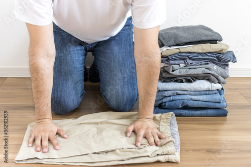 床で衣類の洗濯物を畳んでいる男性