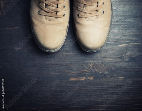 Vintage travel boots on wooden floor background. Top view. Flat lay.