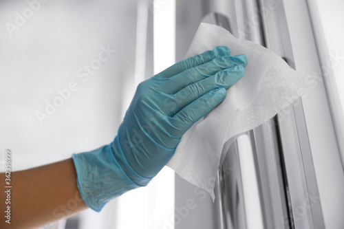 Woman cleaning door handle with wet wipe indoors, closeup