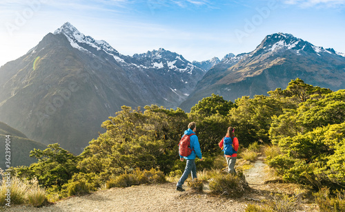 Hiking couple walking on trail at Routeburn Track in New Zealand. Hikers trekking wearing backpacks while tramping on Key Summit Track on vacation at Fiordland National Park, New Zealand.