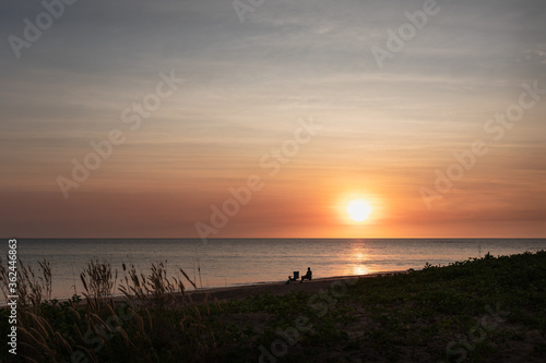 Sunset at Dundee Beach. Person at the beach sitting on a camping chair, with camping gear, looking at the ocean. Fishing destination near Darwin, Northern Territory NT, Australia