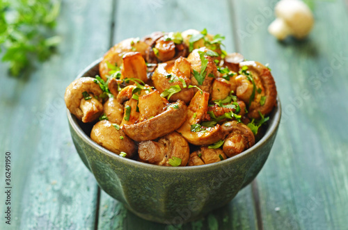 Baked balsamico mushrooms in a rustic green bowl, sprinkled with parsley
