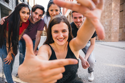 Group of best friends taking a photo with hands in the city - Millennial having fun in summer together - Portrait of people in the street in a moment of break and relax - Concept of selfie and shot