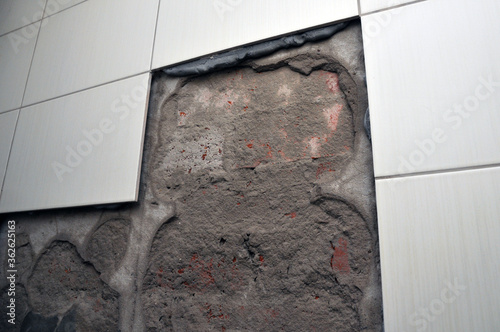 Wall of the toilet room with fallen off tiles, the defect of decoration