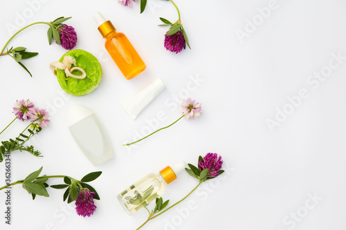 Spa still life with Natural Serums in glass bottle, cream, soap and wildflowers on a white background. Flat lay. copy space. body care concept. 