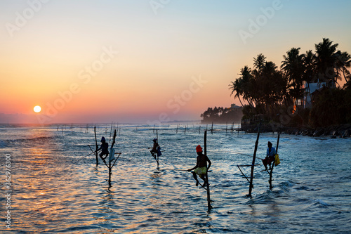 Fishermen on stilts in silhouette at the sunset in Galle, Sri Lanka