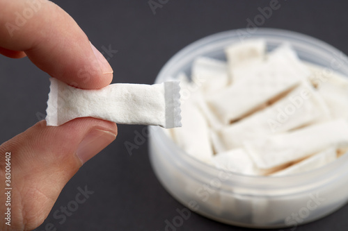 caucasian person holds snus tobacco pouch over black background. copy space. alternative chewing nicotine smoking.