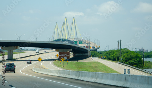 On a highway with a major junction and large cable suspension bridge in the distance