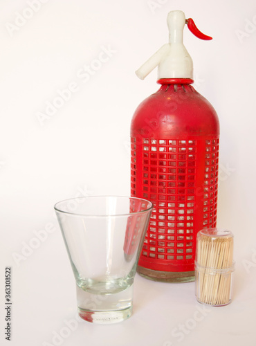 Vasos de vermut rojo con hielo y oliva. Palillos de dientes y sifón de soda de fondo.