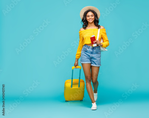 Ethnic tourist with luggage walking towards camera.