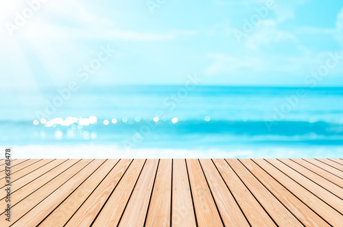 Blur tropical beach with bokeh sun light wave on empty old nature wood table abstract background.