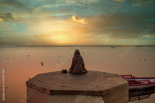 A person is watching beautiful sunrise on the bank of river ganga at ghats of varanasi while meditating