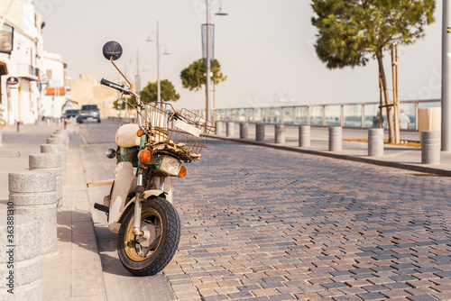 Retro motorbike, moped on the narrow street on the promenade of a small tropical village.