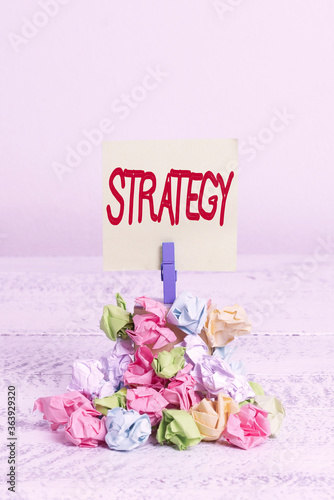 Word writing text Strategy. Business photo showcasing action plan or strategy designed to achieve an overall goal Reminder pile colored crumpled paper clothespin reminder white wooden space