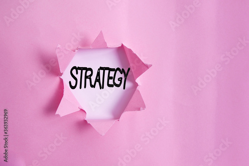 Handwriting text writing Strategy. Conceptual photo action plan or strategy designed to achieve an overall goal Rolled ripped torn cardboard placed above a wooden classic table backdrop