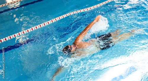 Man swimmer is swimming in the pool, backstroke technique swimming. Shot of swim in motion