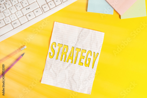 Word writing text Strategy. Business photo showcasing action plan or strategy designed to achieve an overall goal Copy space on notebook above yellow background with pc keyboard on the table