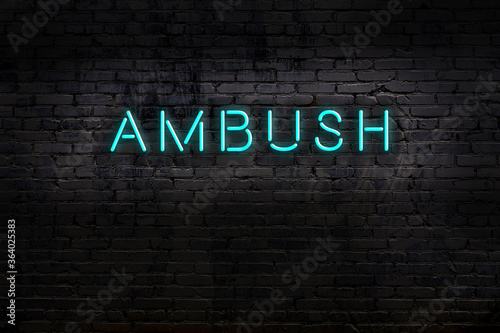 Neon sign. Word ambush against brick wall. Night view