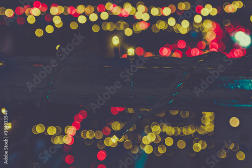 Background of yellow lights, beautiful bokeh, against the background of darkness. Garland with lanterns on a black metal pole. Copy space.