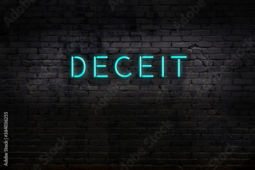 Night view of neon sign on brick wall with inscription deceit